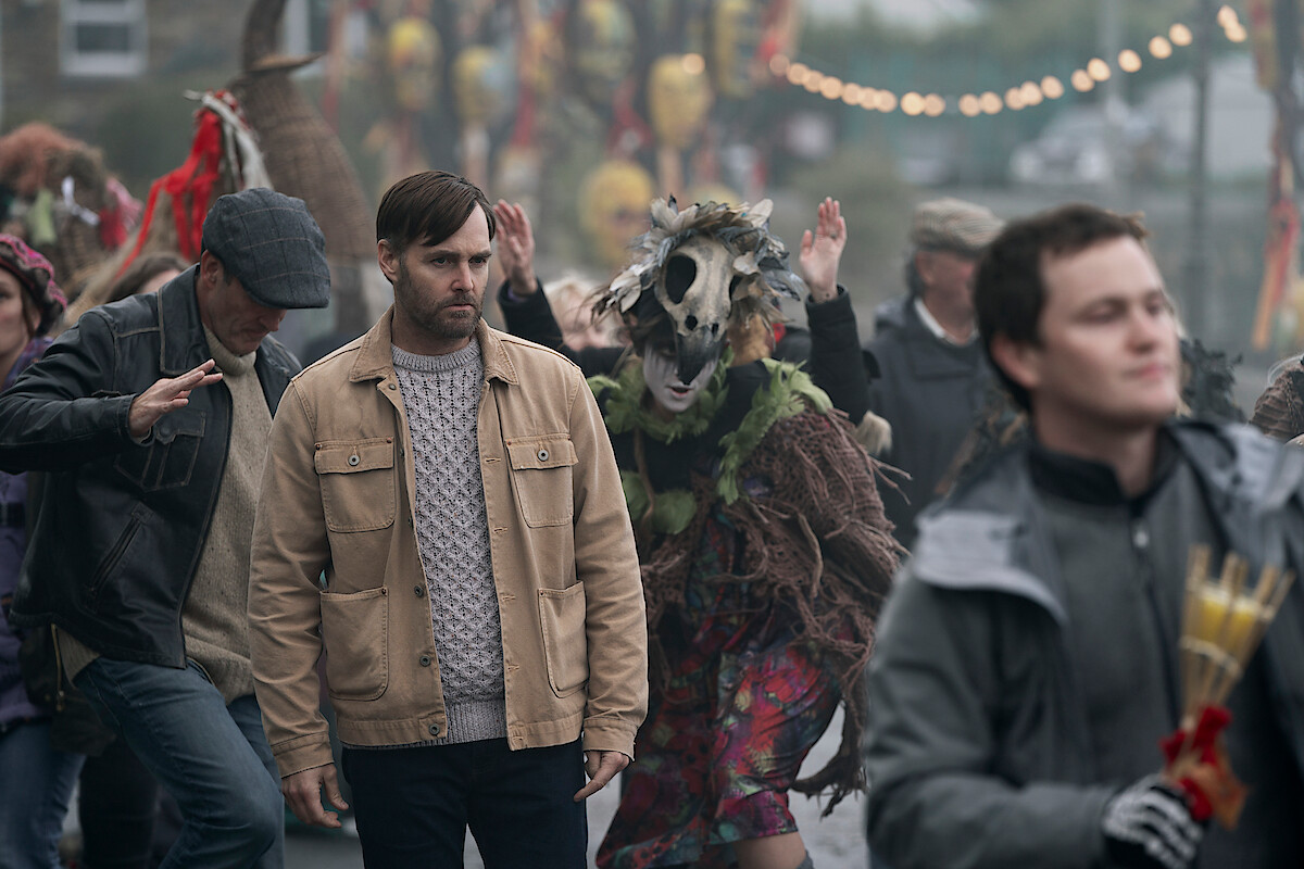 Will Forte as Gilbert Power walks through a crowd at a festival in 'Bodkin'