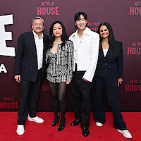 Four people stand together on a red carpet at a Netflix event, posing in front of a branded backdrop. All are dressed in formal or semi-formal attire, smiling and exuding an upbeat, celebratory mood.
