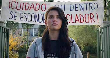 Nicole Wallace as Alma stands at school with a large banner hanging behind her in Season 1 of 'Raising Voices'