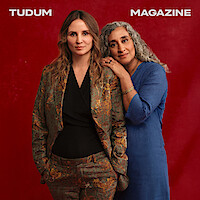 Petra Costa and Geeta Gandbhir pose together against a red background.