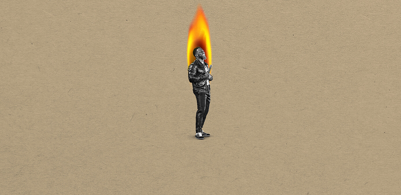 Kevin Hart in black-and-white stands on a tan background, with their head replaced by a large bright flame, suggesting a surreal or artistic concept.