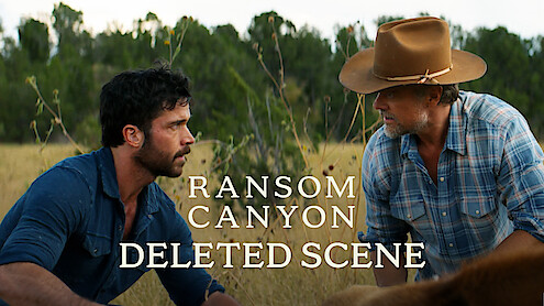 Two men in outdoor rural setting, Yancy Grey (Jack Schumacher) in a blue shirt and Staten Kirkland (Josh Duhamel) in a cowboy hat and plaid shirt, kneeling in tall grass, with trees in the background. Text reads: Ransom Canyon Deleted Scene.
