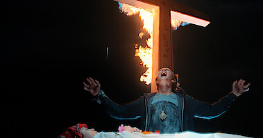 A child standing under a burning cross