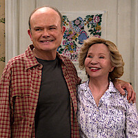 Kurtwood Smith as Red and Debra Jo Rupp as Kitty stand in their kitchen smiling in Part 2 of 'That '90s Show.'