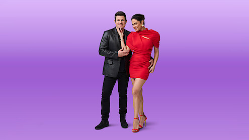 Nick Lachey and Vanessa Lachey pose together against a gradient purple background, standing closely and smiling in a studio setting.