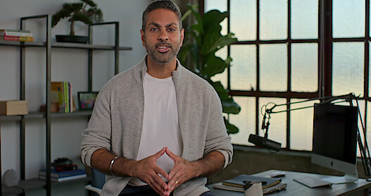 'How to Get Rich' host Ramit Sethi sits in an office addressing the camera in this still image from the Netflix series. 