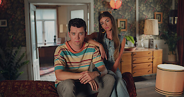 Asa Butterfield as Otis Milburn and Mimi Keene as Ruby Matthews sitting on a couch.