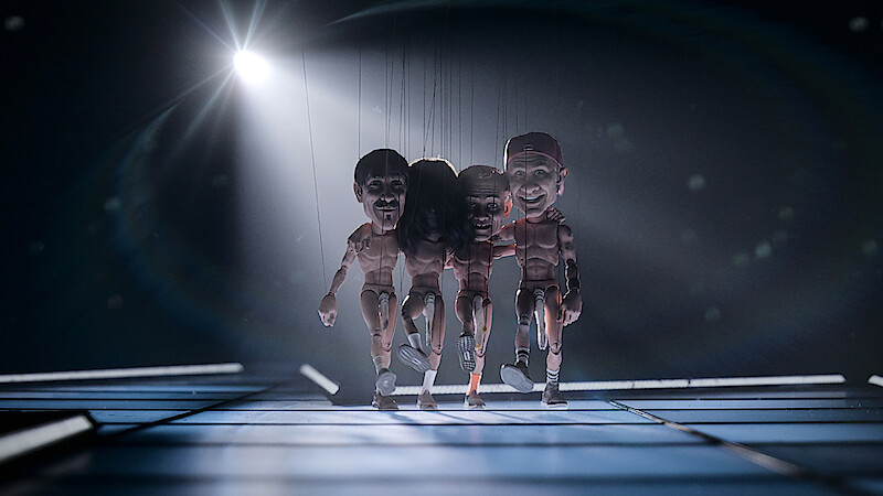 The Red Hot Chili Peppers as marionettes on strings walk across the stage with buff plastic doll bodies exposed to the elements, just the signature sock covering their goods.