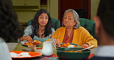Maitreyi Ramakrishnan as Devi and Ranjita Chakravarty as Nirmala in Season 4 of Never Have I Ever, eatting dinner together. 