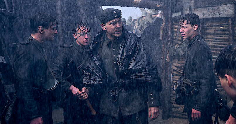 Soldiers standing in the rainy trenches in All Quiet on the Western Front.