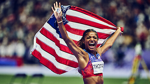 Gabby Thomas celebrating while holding the American flag