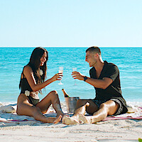 Cast members of 'Too Hot To Handle' Season 6 having a drink on the beach.