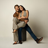 Adria Arjona sits on a Glen Powell's lap.
