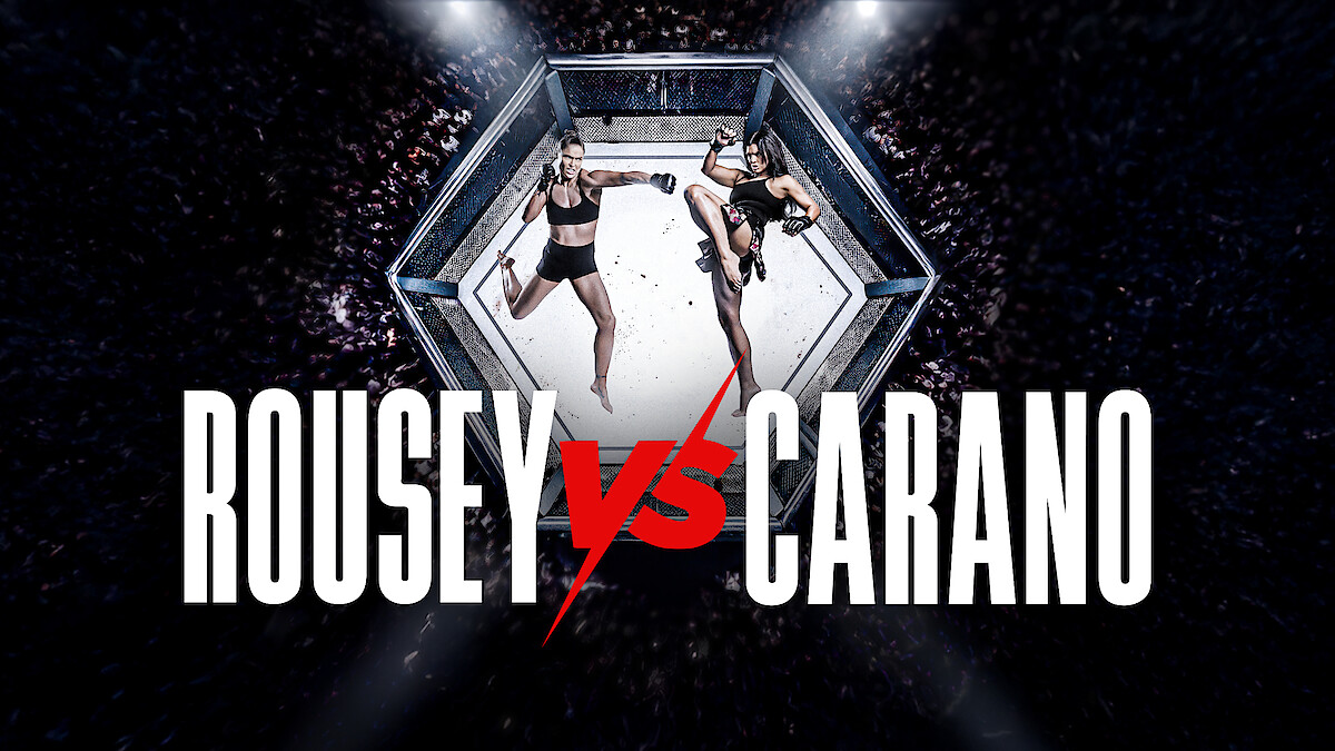 Two female fighters facing off in a mixed martial arts octagon cage, surrounded by a cheering crowd, with large text reading Rousey vs Carano in front.