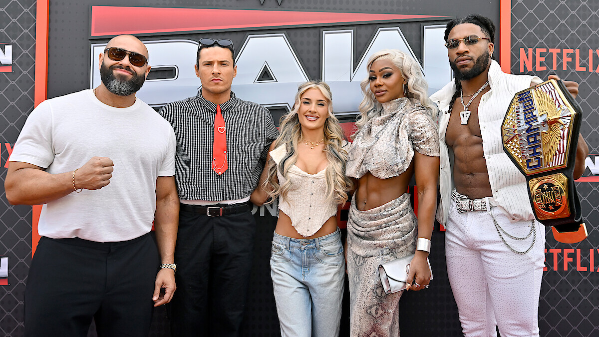 Rusev, Kit Wilson, Tiffany Stratton, Jade Cargill, and Trick Williams posing together on a red carpet at a WWE RAW event, with a branded backdrop. One person is holding an NXT Championship belt. The group is dressed in trendy and distinctive outfits.
