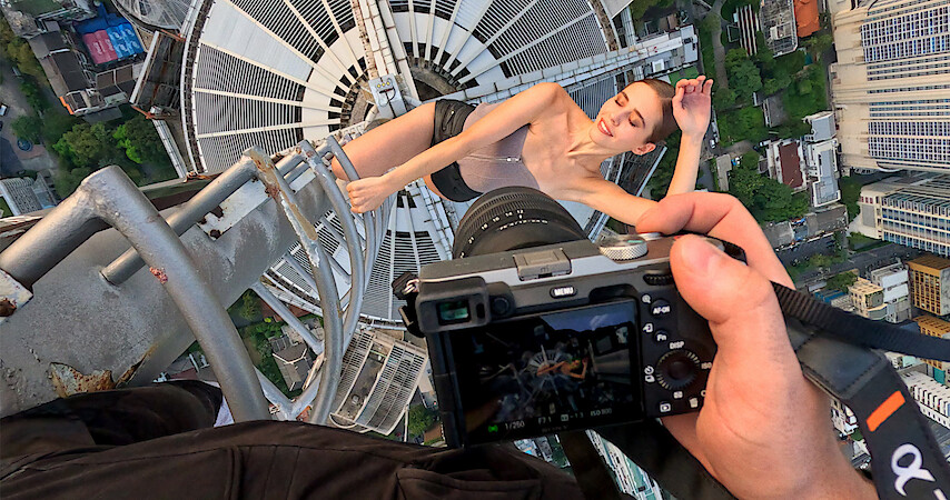 Two people kissing on a crane with a city skyline in the background