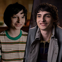 Side-by-side images of Finn Wolfhard at different ages; on the left, he wears a striped shirt in a cozy room, and on the right, he’s older, wearing a jacket, sitting in a warmly lit indoor setting.