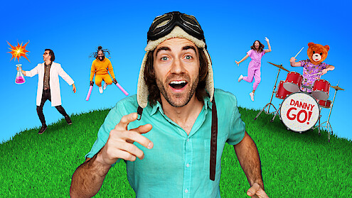 Danny GO! in an aviator hat smiling on grass under blue sky, with scientist holding beaker, person with pink bats, woman jumping, and bear costume playing drums labeled "Danny Go!" in colorful, playful setting.