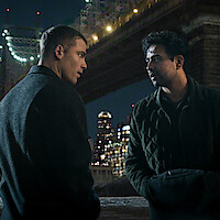 Two men talking under a lit bridge at night with city skyscrapers in the background, urban environment, dramatic and serious atmosphere.