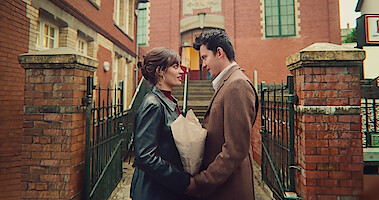 Emma Mackey as Maeve and Asa Butterfield as Otis stand facing each other and holding hands in Season 4 of 'Sex Education.'