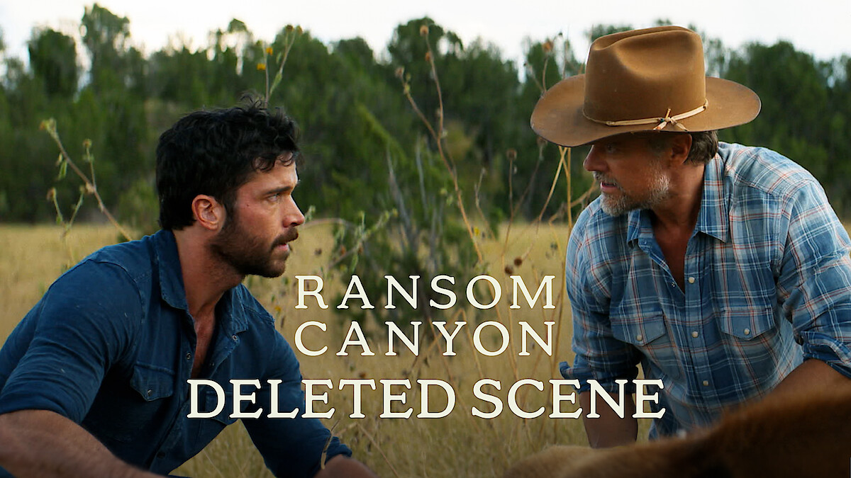 Two men in outdoor rural setting, Yancy Grey (Jack Schumacher) in a blue shirt and Staten Kirkland (Josh Duhamel) in a cowboy hat and plaid shirt, kneeling in tall grass, with trees in the background. Text reads: Ransom Canyon Deleted Scene.