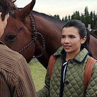 Ashby Gentry as Alex and Nikki Rodriguez as Jackie with a brown horse in 'My Life with the Walter Boys' Season 2.