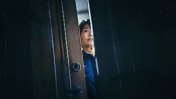 Lee Jung-eun as Yoon Bo-min looks through a slightly opened door in an image from the series 'The Frog.'