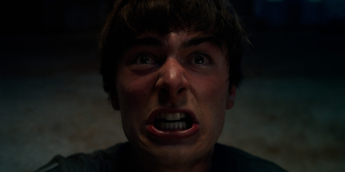 Close-up of Will Byers (Noah Schnapp) expressing intense fear or anger in a dimly lit environment, highlighting raw emotion and tension.