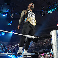 Jey Uso standing on a rope with his belt on facing the crowd.