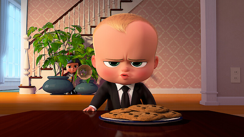 Animated baby in a suit sits at a table with a plate of cookies, looking serious, while a child hides behind potted plants in a cozy home with staircase and wallpaper in the background.