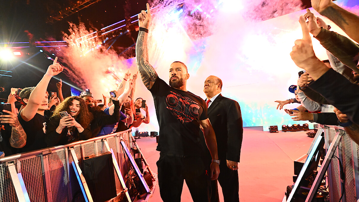 Roman Reigns enters greeting the crowd with pyrotechnics going off behind him.