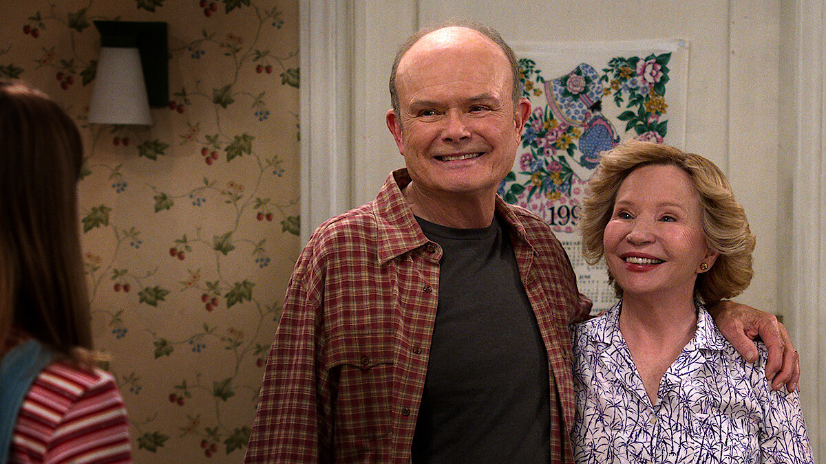 Kurtwood Smith as Red and Debra Jo Rupp as Kitty stand in their kitchen smiling in Part 2 of 'That '90s Show'