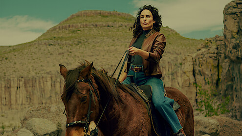 Ana Serradilla as Perla in 'Sisters' Feud' rides a horse in front of mountains in a desert landscape.