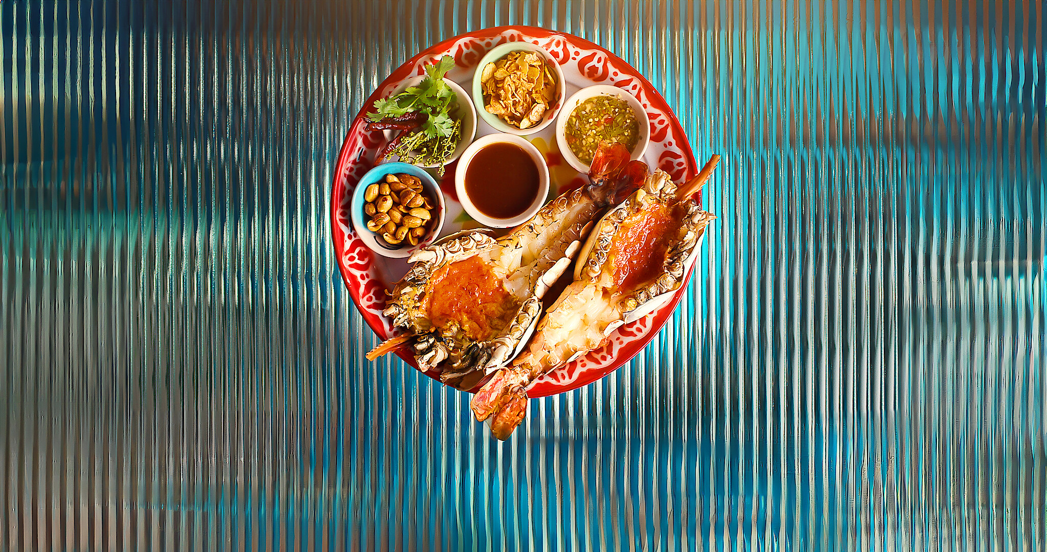 A plate of delicious looking lobster and dipping sauces on top of a glass table