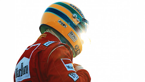 Ayrton Senna (Gabriel Leone) wears a red Marlboro jacket and a green-and-yellow helmet as he gears up to race.