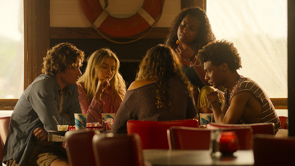 Photo: netflix.com Five young people sit around a table in a retro diner with red chairs and nautical decor, talking and sharing drinks