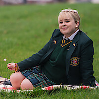 Nicola Coughlan as Claire Devlin sitting on grass with a flower crown in Derry Girls.
