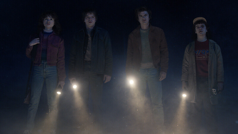 Natalia Dyer as Nancy Wheeler, Charlie Heaton as Jonathan Byers and Joe Keery as Steve Harrington, standing in the dark with flashlights pointed forward in 'Stranger Things 5.'
