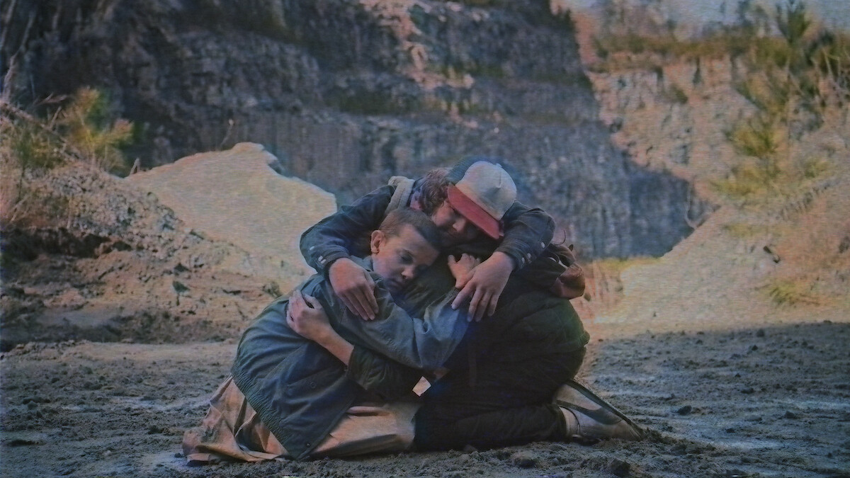 Eleven, Dustin, and Mike hug each other in 'Stranger Things' Season 1.