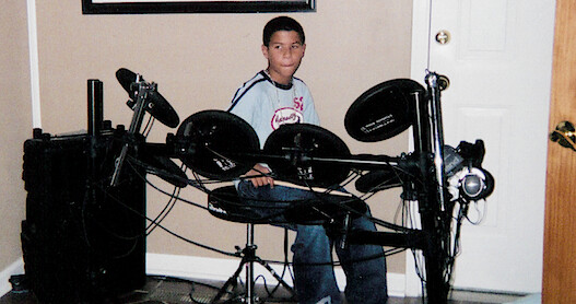 A picture of Bubba Wallace as a teen playing at a drum kit