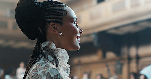 India Amarteifio as Young Queen Charlotte and Corey Mylchreest as Young King George dancing.