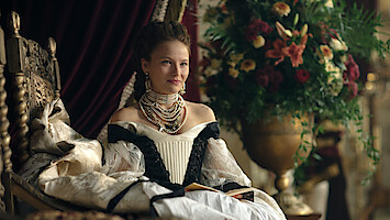 Uma mulher veste trajes de realeza e se senta em um trono na série 'The Empress'