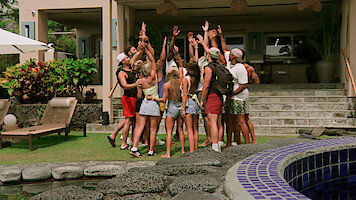 Peter Cipriano, Braeden Holliday, Scarlett Bentley, Shyanne Blankenship, Kaylee Needham, Bradley Bobbit, and Clint Smith in summer clothes stand in a circle with raised hands outside a modern villa, surrounded by greenery, lounge chairs, and a pool.