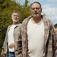 Franck Dubosc, Jean Reno, Alizée Caugnies, Suzanne Clément, and Raphael Romand stand in an open field with trees and a hill behind them in an image from the film 'Family Pack.'