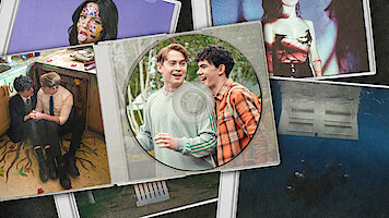 Kit Connor as Nick and Joe Locke as Charlie smile together on a CD cover, surrounded by album artwork from songs in Season 3 of 'Heartstopper'