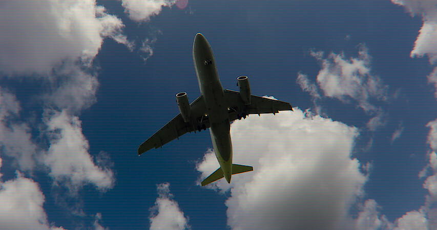 A jet flies through the air with blue sky and clouds.