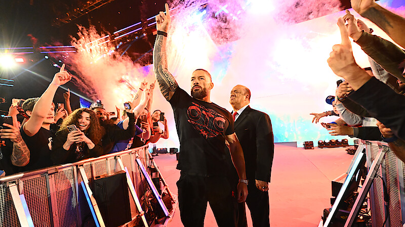 Roman Reigns enters greeting the crowd with pyrotechnics going off behind him.