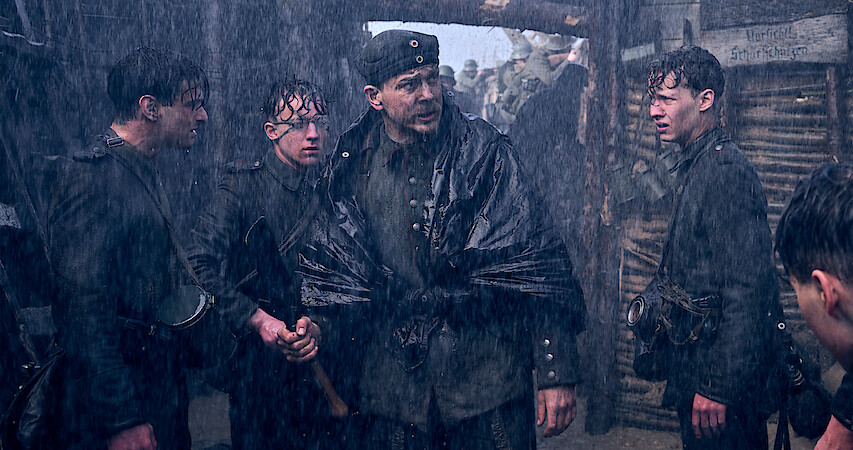 Soldiers standing in the rainy trenches in All Quiet on the Western Front.