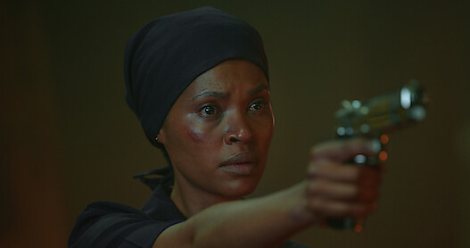 Zenzi (Gail Mabalane) holds a pistol