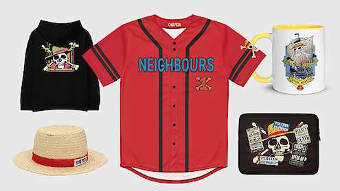 Group of assorted merchandise on a light background: black hoodie, straw hat, red "NEIGHBOURS" jersey, pirate-themed mug, and a black pouch with skull and pirate graphics.